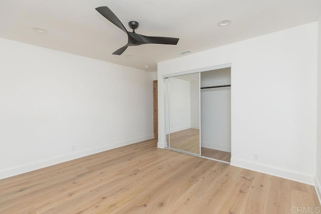 unfurnished bedroom featuring a closet, a ceiling fan, light wood-style floors, and baseboards