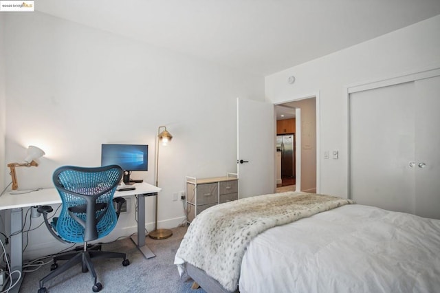 bedroom with carpet floors, a closet, and stainless steel fridge