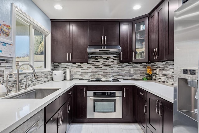 kitchen featuring tasteful backsplash, sink, exhaust hood, and appliances with stainless steel finishes