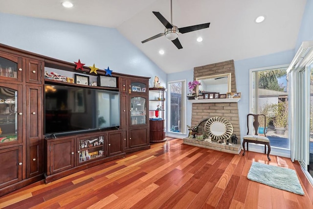 living room with ceiling fan, high vaulted ceiling, hardwood / wood-style floors, and a fireplace