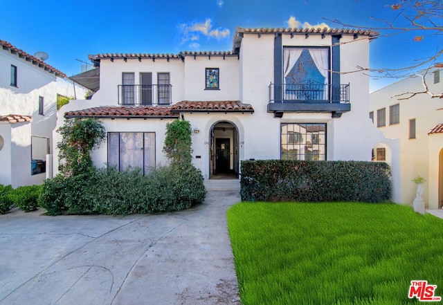 mediterranean / spanish-style house featuring a front yard and a balcony