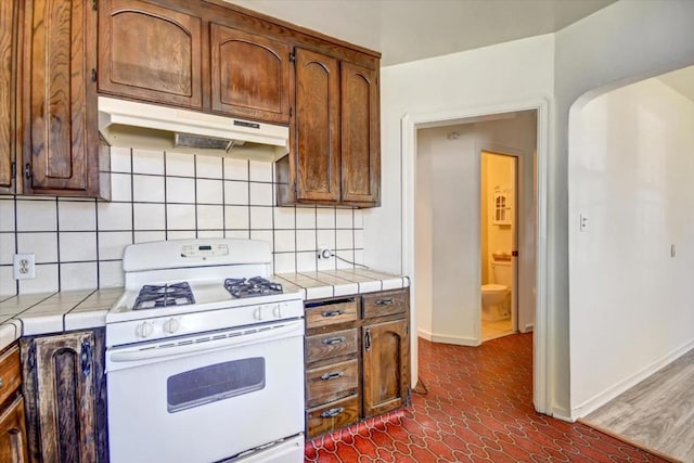 kitchen featuring gas range gas stove, tile counters, and tasteful backsplash