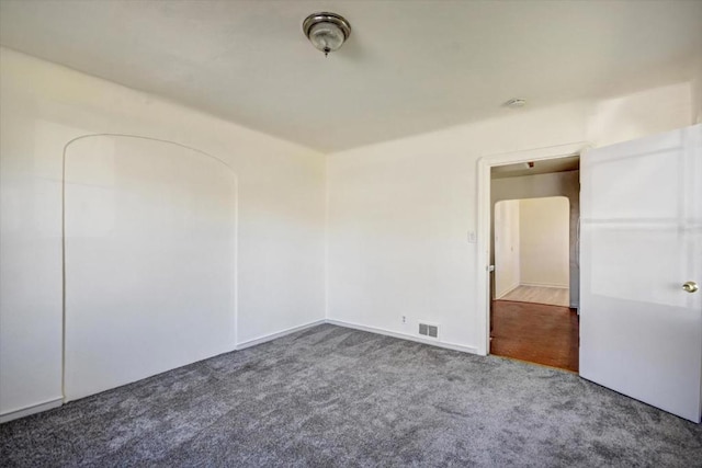 unfurnished room featuring dark carpet