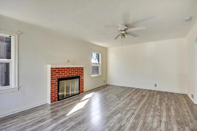 unfurnished living room with ceiling fan, a brick fireplace, and light hardwood / wood-style floors