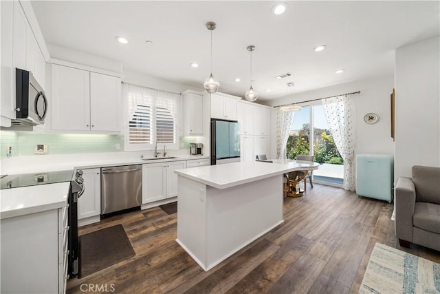 kitchen with white cabinetry, stainless steel appliances, dark hardwood / wood-style floors, pendant lighting, and sink