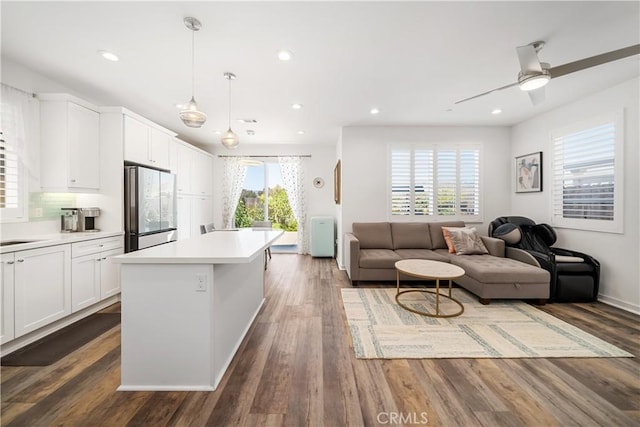 kitchen with white cabinetry, backsplash, fridge, decorative light fixtures, and a kitchen island