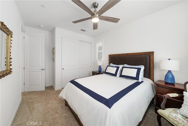 bedroom with ceiling fan, light colored carpet, and a closet