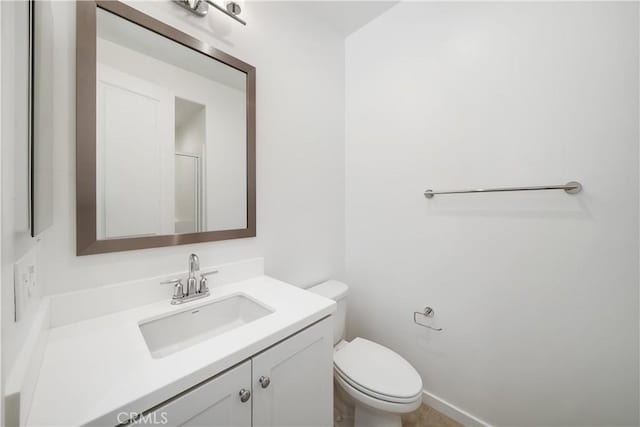 bathroom featuring toilet, a shower with shower door, and vanity