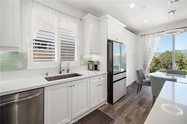 kitchen featuring appliances with stainless steel finishes, tasteful backsplash, dark wood-type flooring, white cabinets, and sink