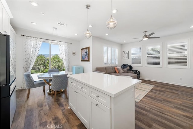 kitchen with dark wood-type flooring, white cabinetry, pendant lighting, and refrigerator