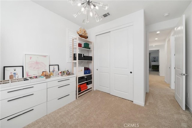 bedroom with a closet, light carpet, and a chandelier