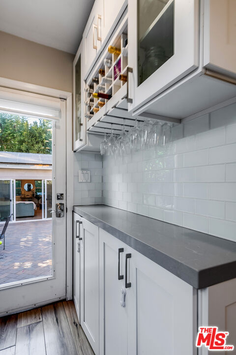 kitchen featuring decorative backsplash, white cabinetry, and hardwood / wood-style floors