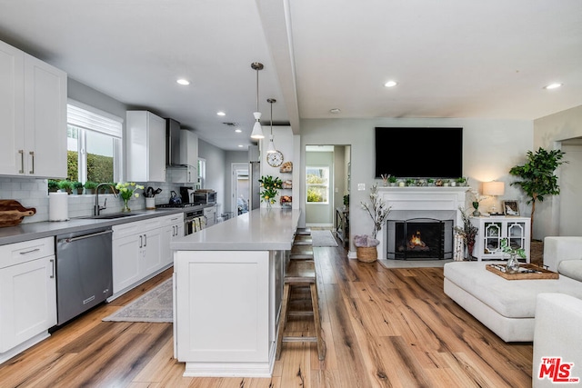 kitchen featuring sink, dishwasher, white cabinets, and a center island