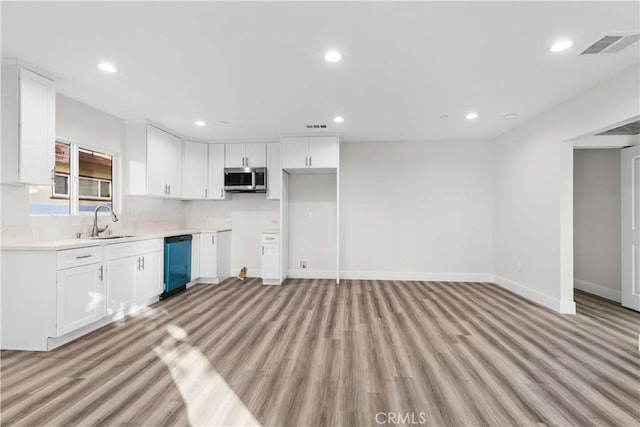 kitchen with black dishwasher, sink, white cabinetry, and light hardwood / wood-style flooring