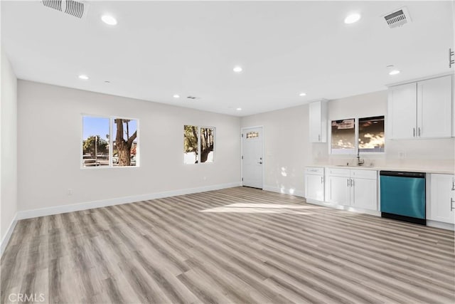 interior space with stainless steel dishwasher, sink, white cabinetry, and light hardwood / wood-style flooring