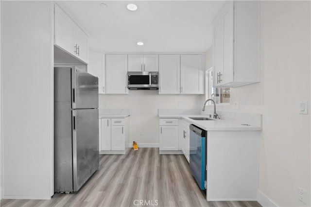 kitchen with sink, white cabinetry, light hardwood / wood-style flooring, and stainless steel appliances