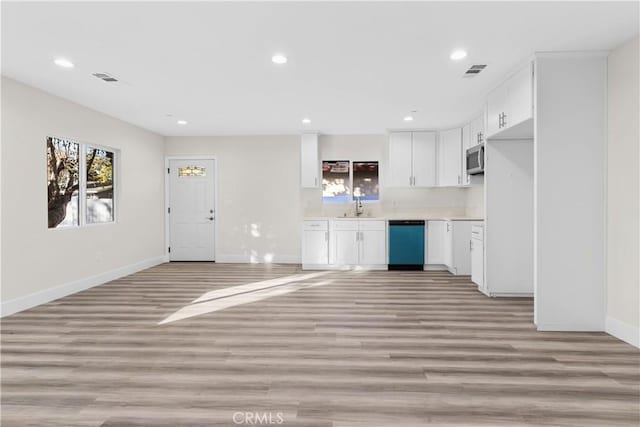 kitchen featuring white cabinetry, sink, dishwashing machine, and light hardwood / wood-style flooring