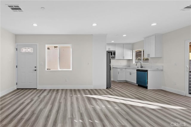 kitchen featuring white cabinetry, dishwashing machine, light wood-type flooring, stainless steel refrigerator, and sink