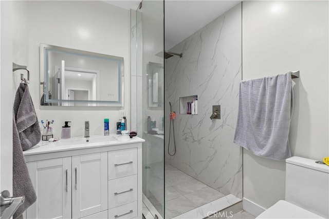 bathroom with toilet, tiled shower, and vanity