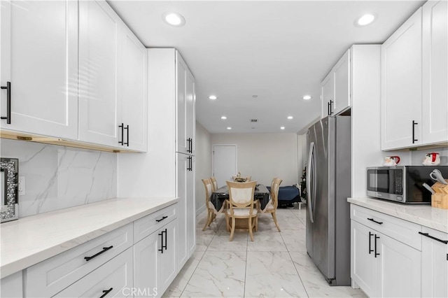 kitchen featuring appliances with stainless steel finishes, backsplash, white cabinets, and light stone counters