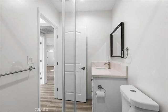 bathroom with toilet, vanity, and hardwood / wood-style floors