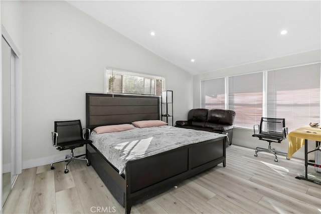 bedroom featuring light wood-type flooring, a closet, and high vaulted ceiling