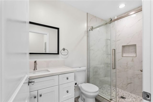 bathroom with an enclosed shower, vanity, and toilet