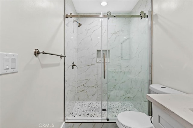 bathroom featuring a shower with door, toilet, and vanity