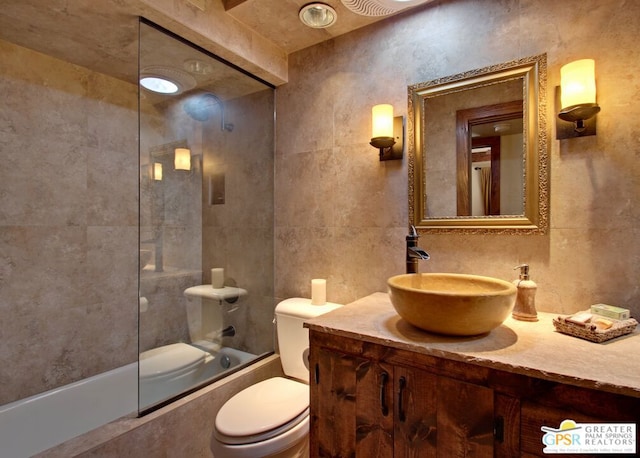 full bathroom with vanity, toilet, tile walls, and tiled shower / bath