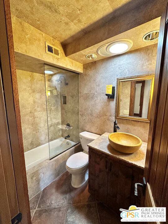 full bathroom with tile walls, toilet, vanity, and tiled shower / bath