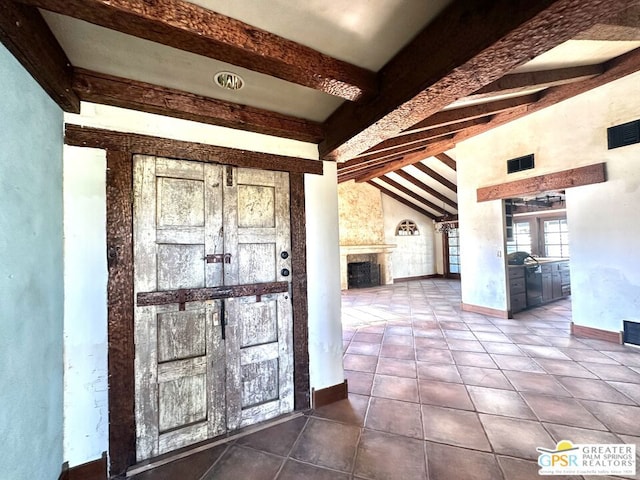 entrance foyer with a large fireplace, vaulted ceiling with beams, and tile patterned floors