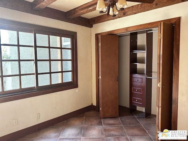 unfurnished bedroom featuring a closet and beamed ceiling