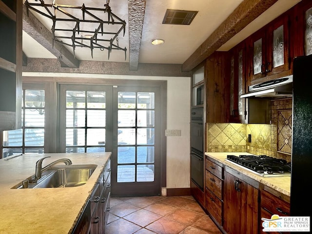 kitchen with black appliances, light tile patterned floors, sink, beam ceiling, and backsplash