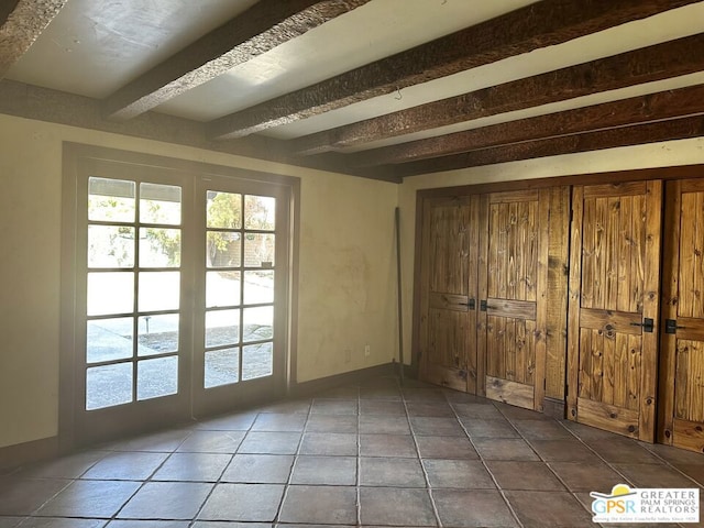 interior space with dark tile patterned flooring and beam ceiling