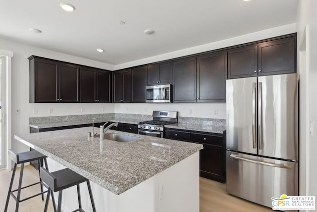 kitchen featuring stainless steel appliances, a kitchen island with sink, dark brown cabinetry, and sink