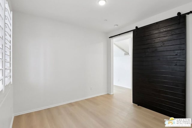 empty room featuring a barn door and light hardwood / wood-style floors