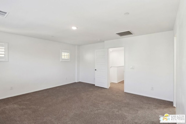 unfurnished room featuring dark colored carpet