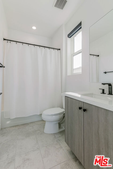 full bathroom featuring toilet, vanity, and shower / tub combo with curtain