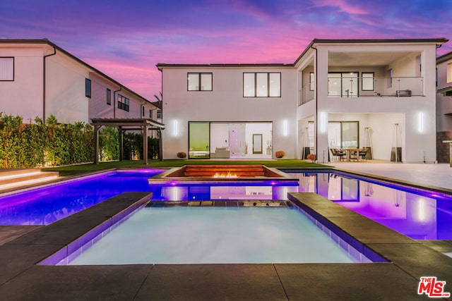 pool at dusk featuring a pergola, a patio, and an in ground hot tub