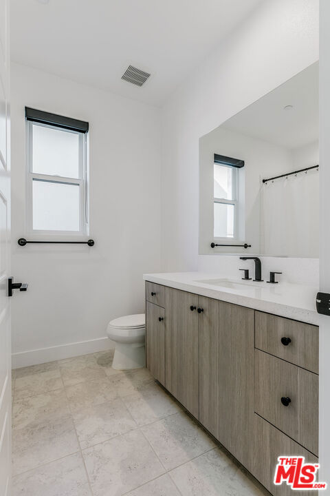 bathroom with toilet, tile patterned flooring, and vanity