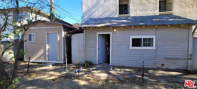 rear view of property featuring a storage shed