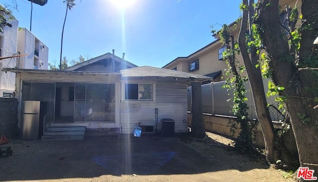 rear view of property with central AC unit and a sunroom