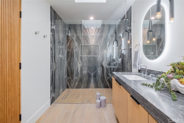 bathroom featuring walk in shower, vanity, and a skylight