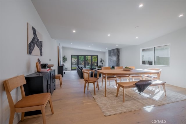 dining area with vaulted ceiling, light hardwood / wood-style flooring, and french doors