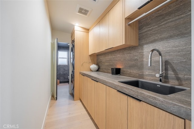 kitchen with light brown cabinetry, light hardwood / wood-style floors, tasteful backsplash, and sink