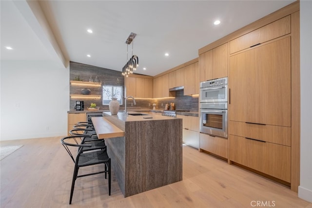 kitchen featuring light brown cabinetry, sink, light hardwood / wood-style flooring, and a kitchen island with sink