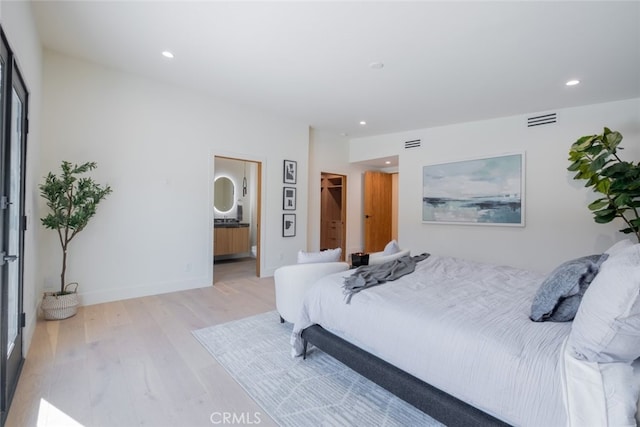 bedroom featuring ensuite bathroom and light hardwood / wood-style flooring