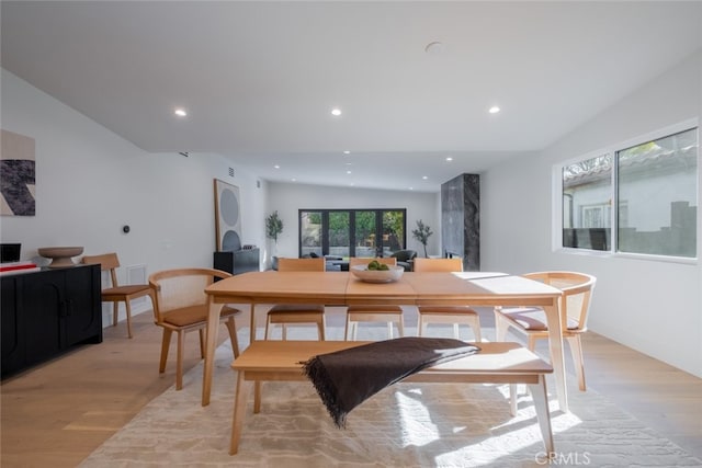 dining area with light wood-type flooring, vaulted ceiling, and a wealth of natural light