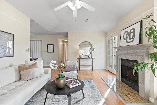 living room with a premium fireplace, ceiling fan, and light hardwood / wood-style flooring