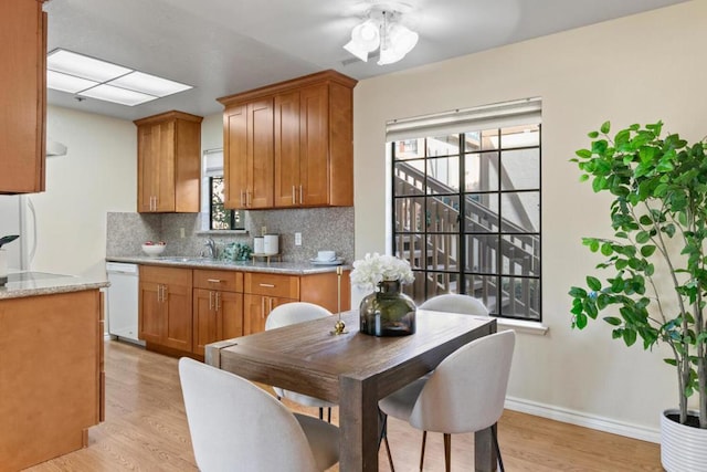 kitchen featuring tasteful backsplash, plenty of natural light, white dishwasher, and light wood-type flooring